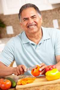 Man smiling and cutting peppers